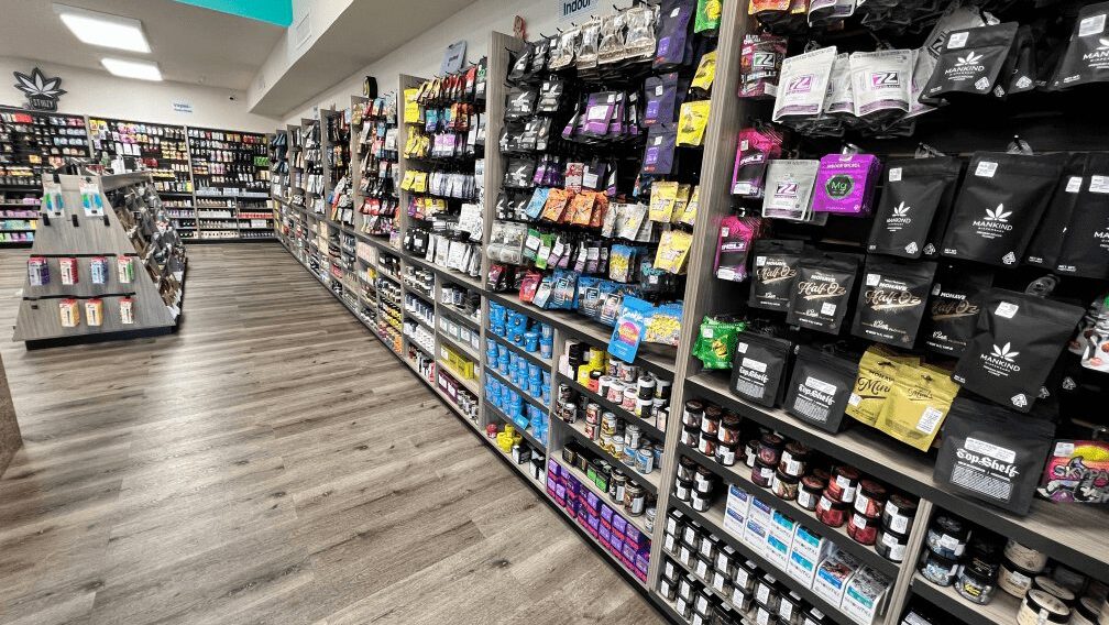 The Cake House Santa Rosa Dispensary with wood-floored interior with shelves displaying cannabis products, in colorful packaging and signs overhead.
